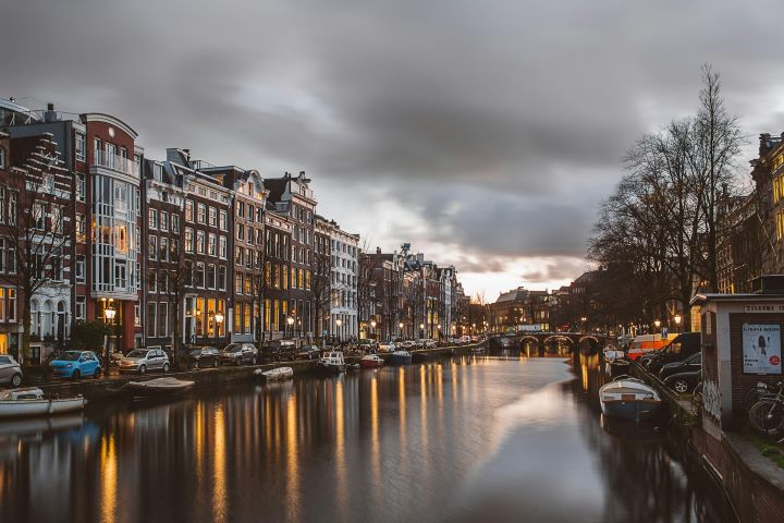 Evening view of Amsterdam, Netherlands with historic canal houses reflecting in the water and soft winter lights glowing