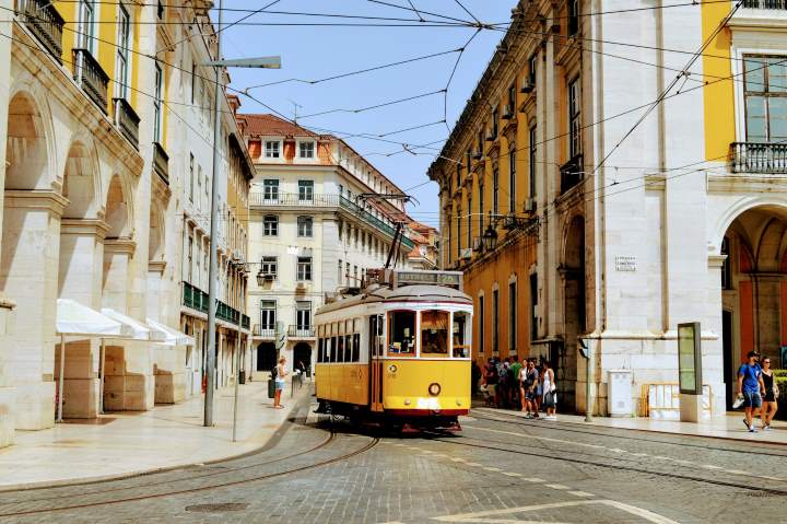 Charming yellow tram passing through the historic streets of Lisbon, Portugal surrounded by classic European architecture — a must-visit destination in Europe in December, featured in Trekhops winter travel guide.