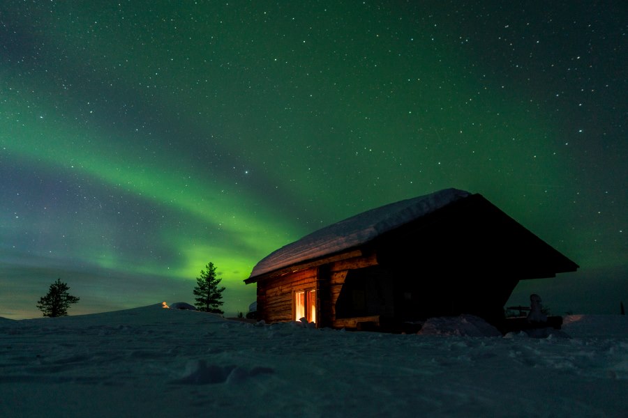 A cozy snow-covered cabin under the Northern Lights in Finland, highlighting why it's one of the best countries to visit in December for a magical winter experience.