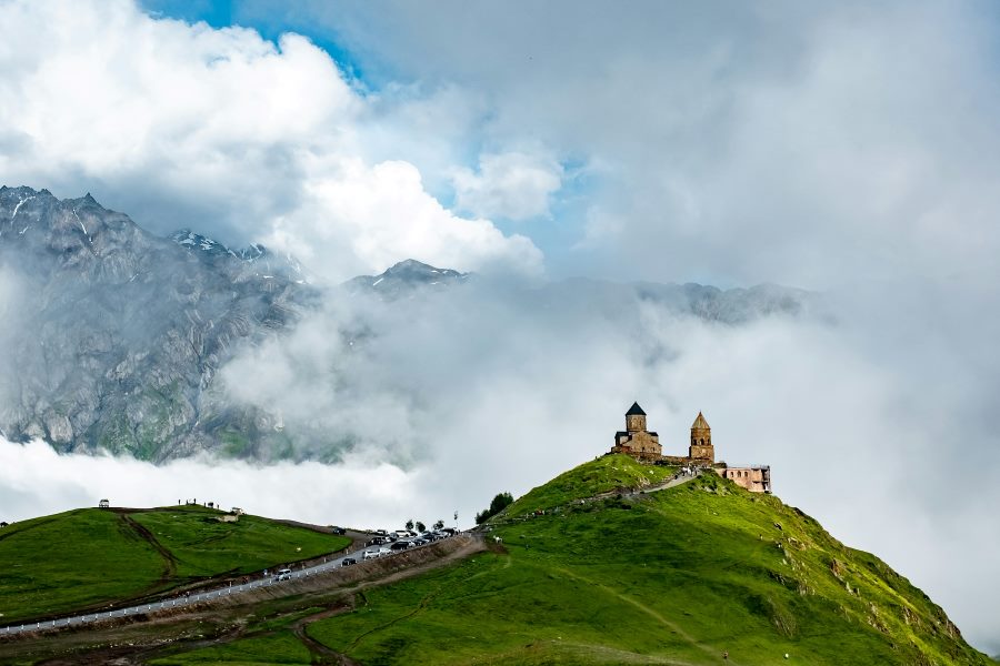 A hilltop church surrounded by misty mountains and lush greenery in Georgia—an emerging eco-friendly country to visit in December for its natural beauty and sustainable travel experiences.