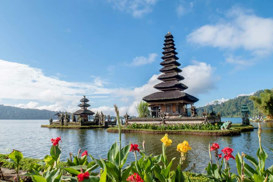 A beautiful view of the iconic Ulun Danu Beratan Temple surrounded by a serene lake and vibrant flowers in Bali, Indonesia — one of the top countries to visit visa-free from India.