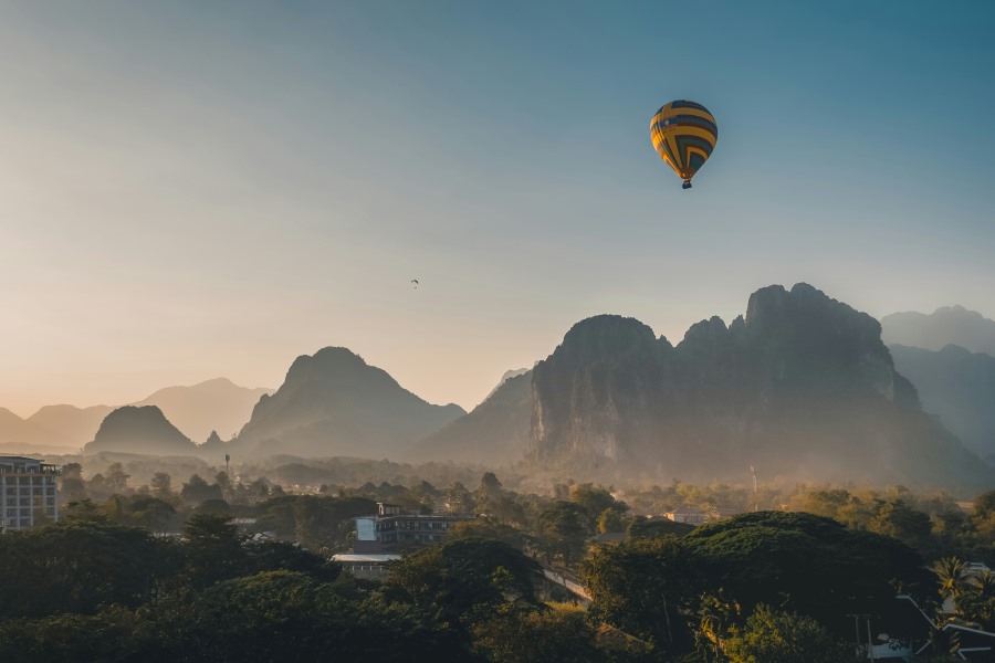 A hot air balloon floats peacefully above a misty mountain landscape during sunrise in Vang Vieng, Laos — one of the top countries to visit visa-free from India.